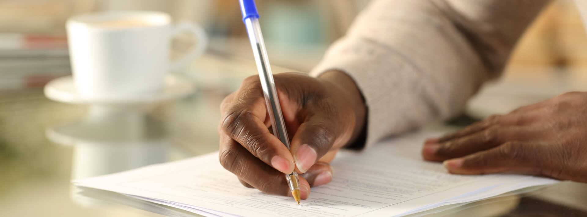 Manos de hombre negro rellenando un formulario sobre un escritorio